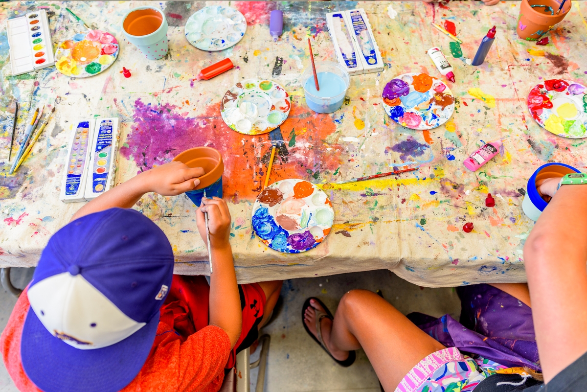Children painting on a messy paint covered table